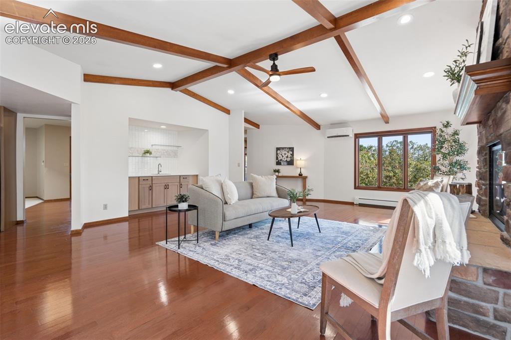 Image 9 of 50: Vaulted ceiling with exposed wood beams, wood-finish flooring, stone-clad f