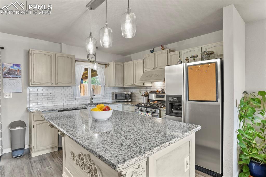 Image 7 of 31: Kitchen featuring pendant lighting, stone countertops, stainless steel appl