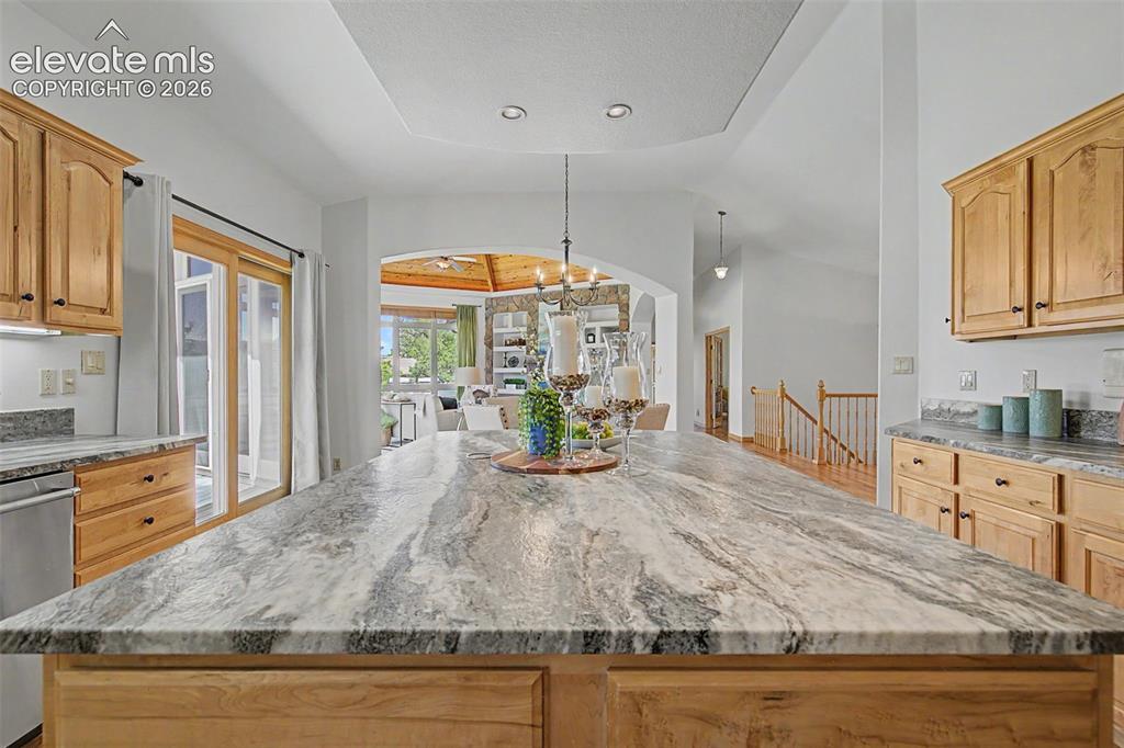 Image 11 of 50: Spacious kitchen island with a patterned countertop, recessed lighting, woo