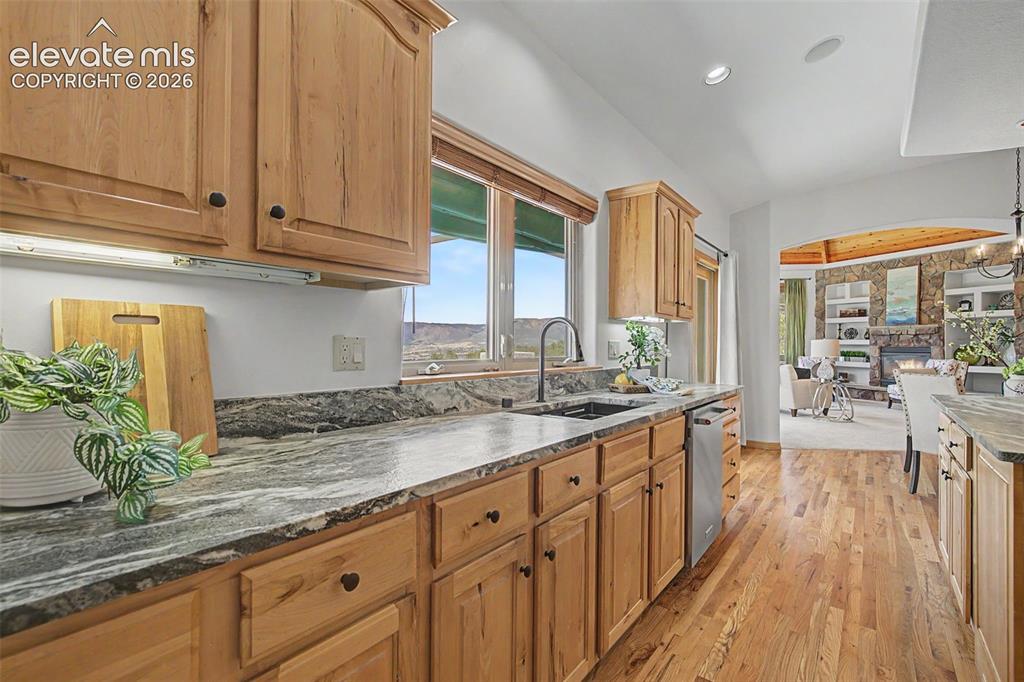 Image 12 of 50: Kitchen featuring wood-finish cabinetry with black hardware, stone countert