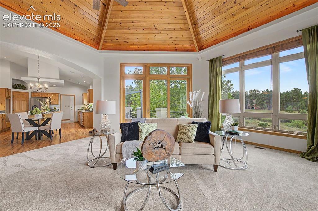 Image 14 of 50: Vaulted wood-paneled ceiling with a central fan, large windows with natural