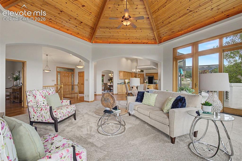 Image 19 of 50: Expansive living area featuring a vaulted wood-paneled ceiling, large windo
