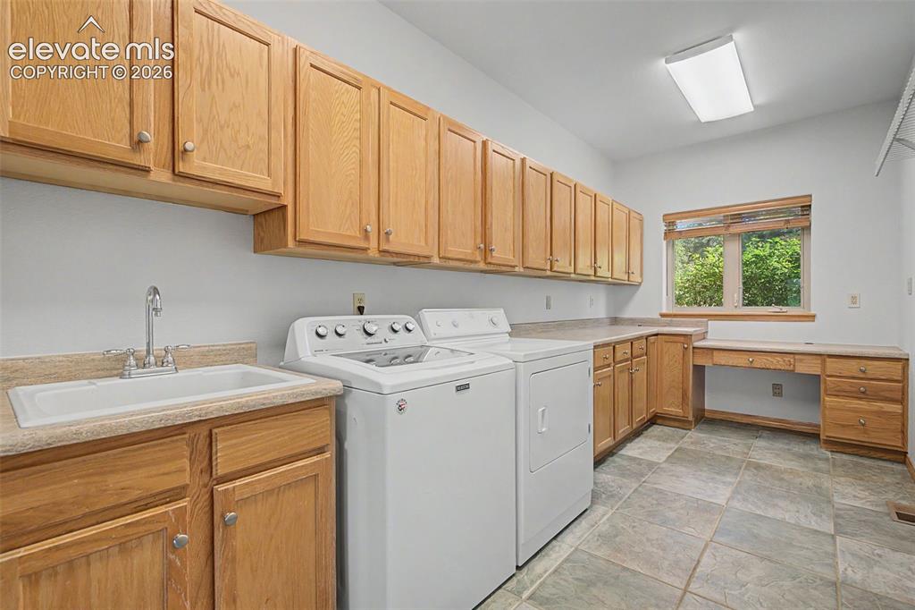 Image 29 of 50: Spacious utility room featuring extensive natural wood cabinetry, a built-i