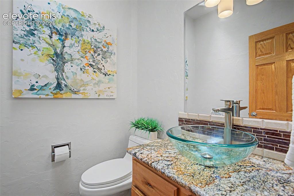 Image 30 of 50: Contemporary vanity featuring a glass vessel sink, granite countertop, and