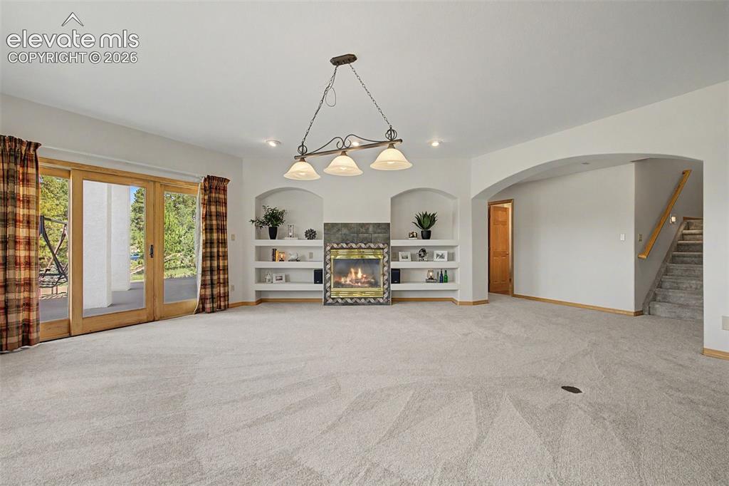 Image 32 of 50: Spacious room featuring light-colored carpeting and a stone-faced fireplace