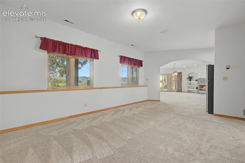 Image 36 of 50: Carpeted interior space featuring two windows, an arched doorway, and light