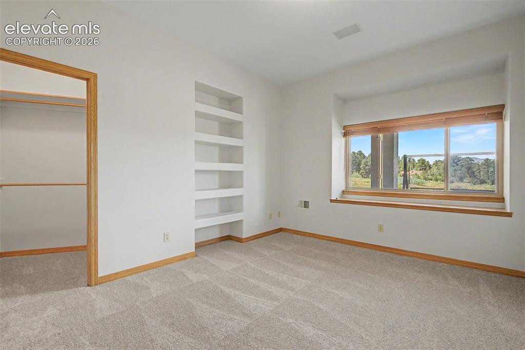 Image 38 of 50: Light-filled room featuring a large window with a wood-finish sill, built-i
