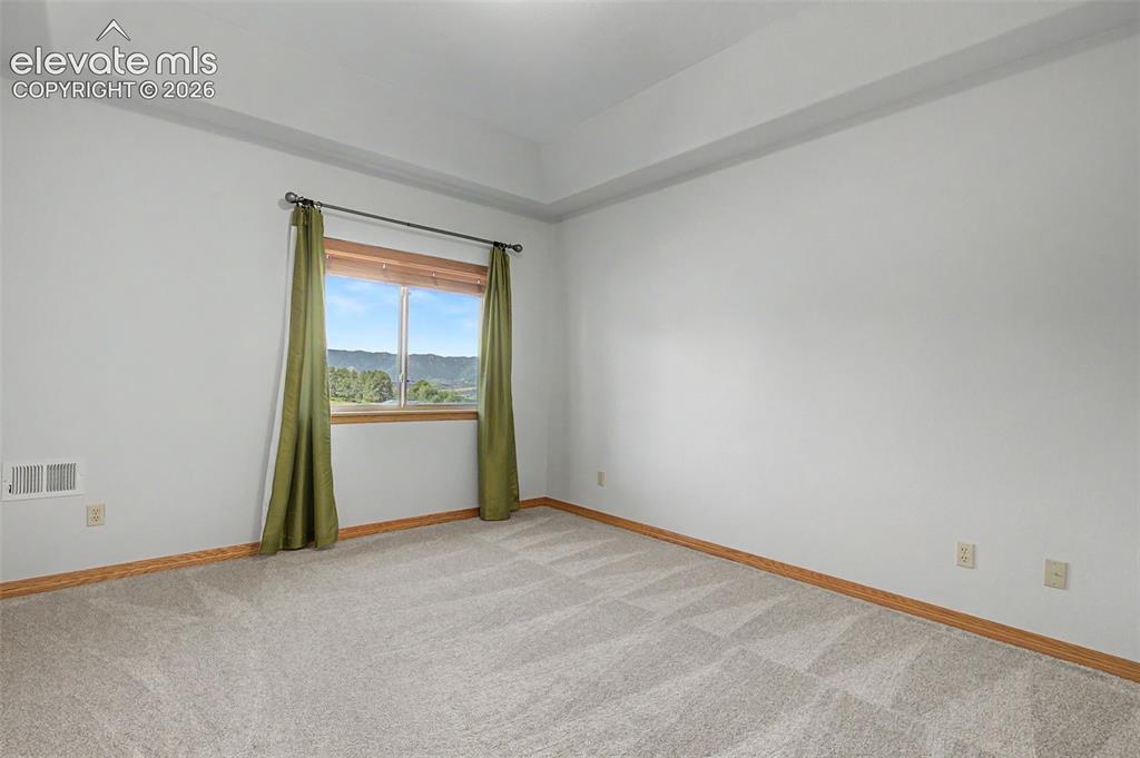 Image 40 of 50: Carpeted room featuring a large window with wood trim, offering a backdrop