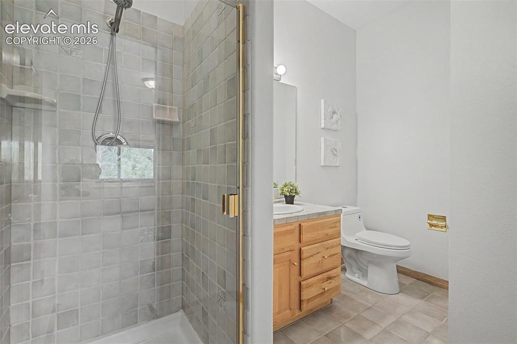 Image 42 of 50: Shower with glass enclosure, gold-toned hardware, and square tile surround