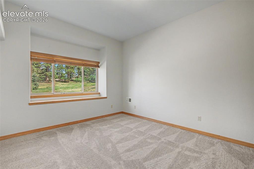 Image 43 of 50: Recessed window with wood-finish trim, beige blinds, and a natural landscap