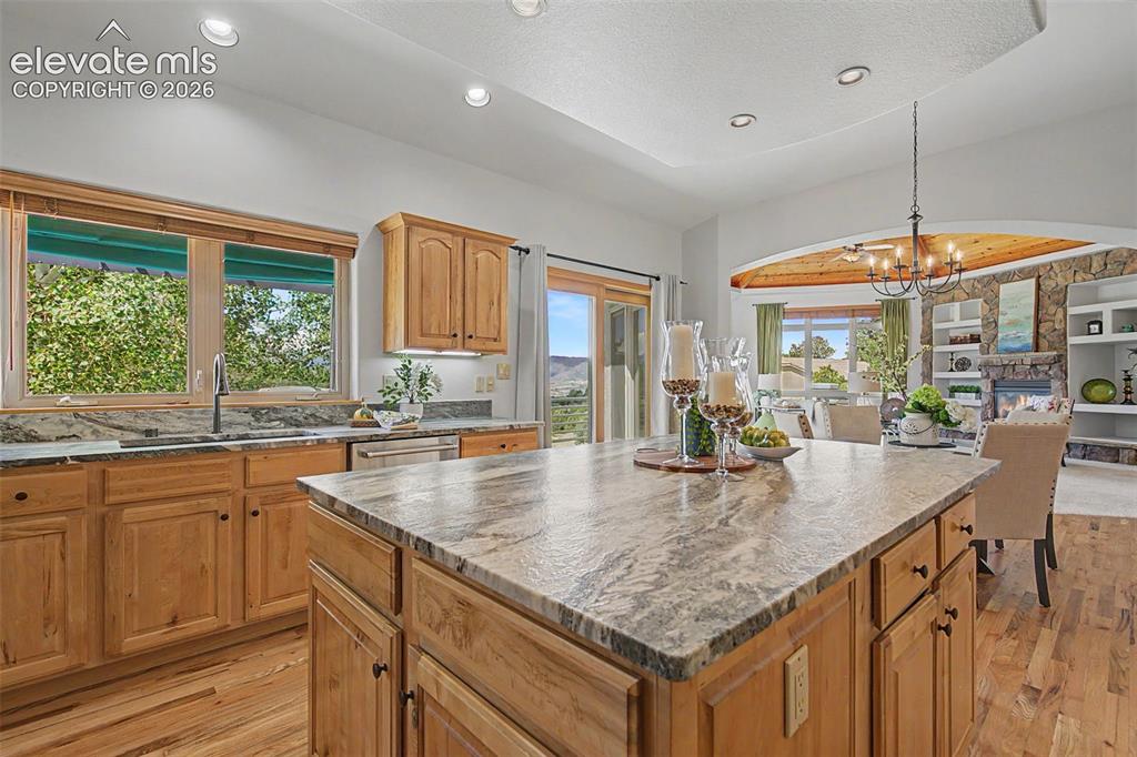 Image 8 of 50: Kitchen featuring an expansive center island with stone-finish countertops,