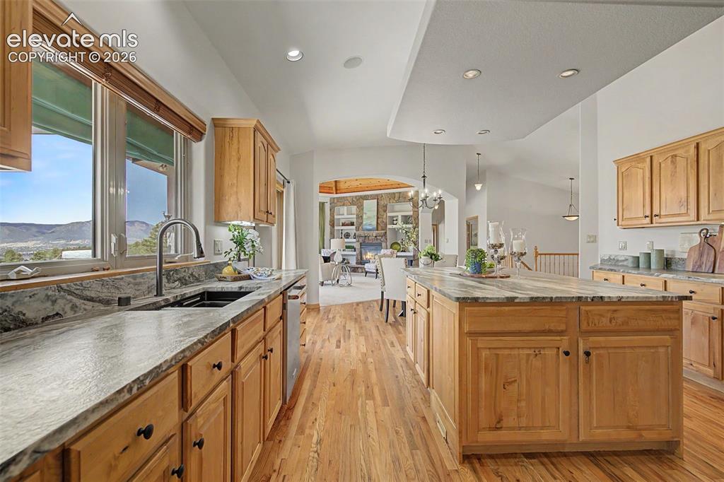 Image 9 of 50: Spacious kitchen featuring light wood cabinetry, stone countertops, a large