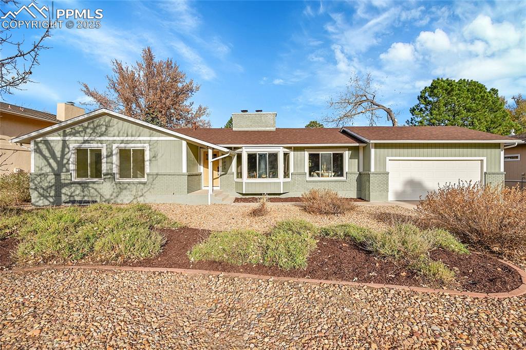 Caption: Ranch-style home with brick siding, a chimney, a garage, and a shingled roof