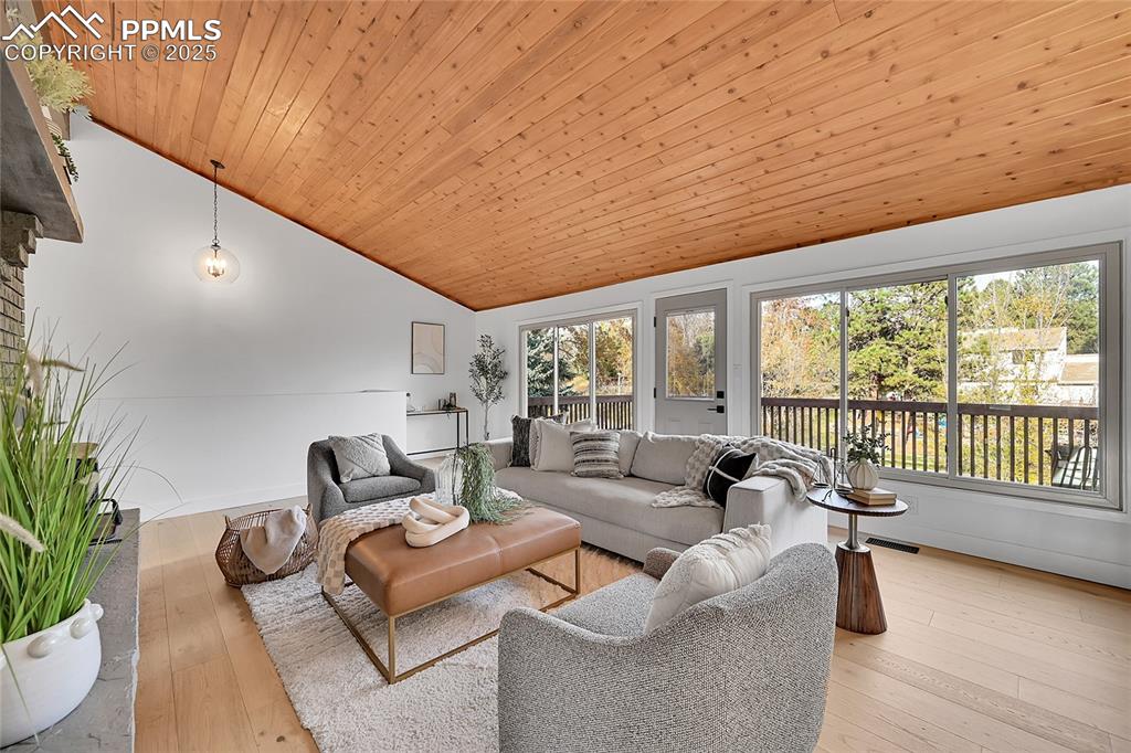Image 17 of 40: Living room featuring light wood-style flooring, wooden ceiling, and high v