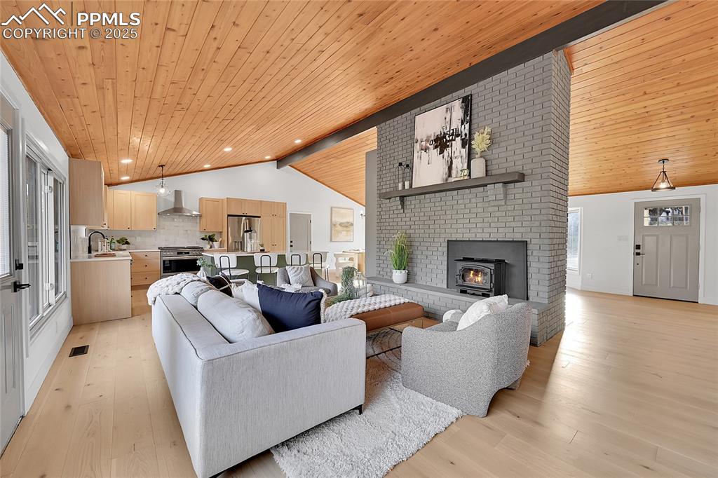 Image 19 of 40: Living area featuring wooden ceiling, light wood-style floors, high vaulted