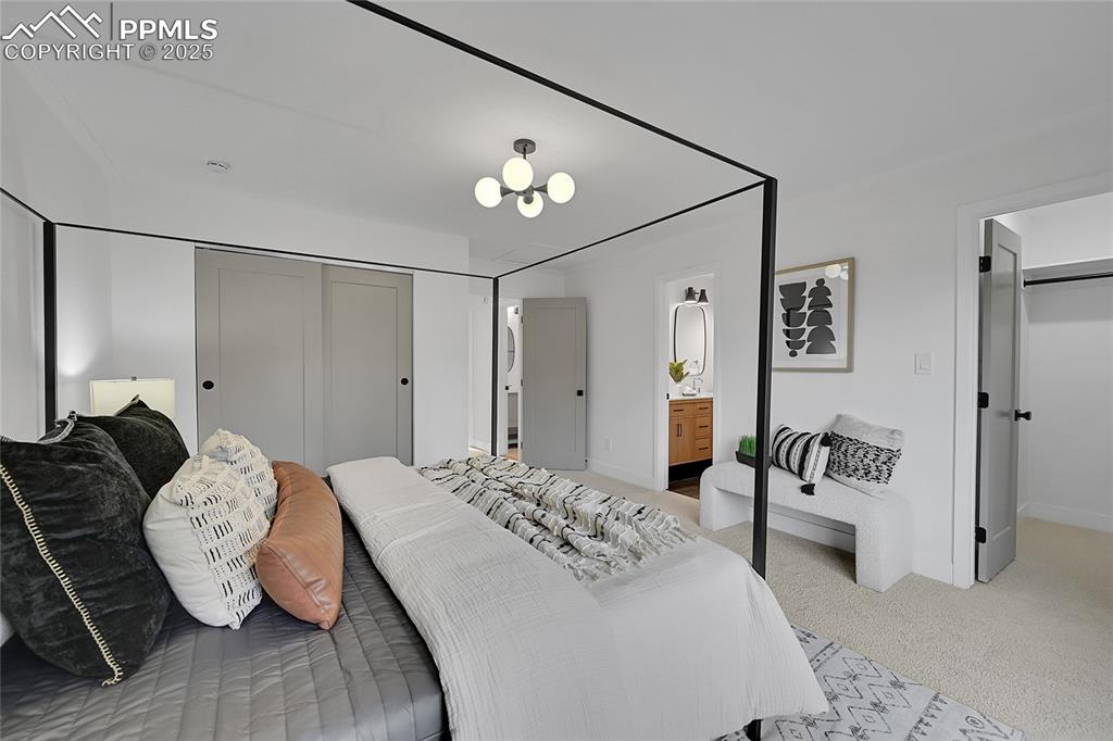 Image 24 of 40: Bedroom featuring light colored carpet, a chandelier, and ensuite bathroom