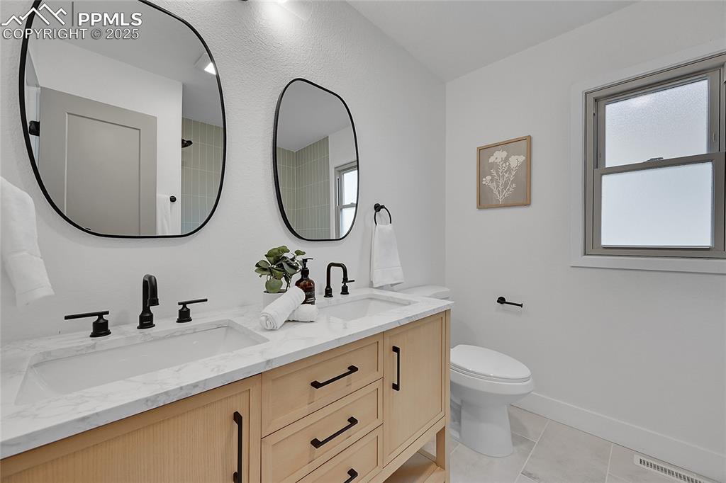 Image 28 of 40: Bathroom with double vanity and light tile patterned floors