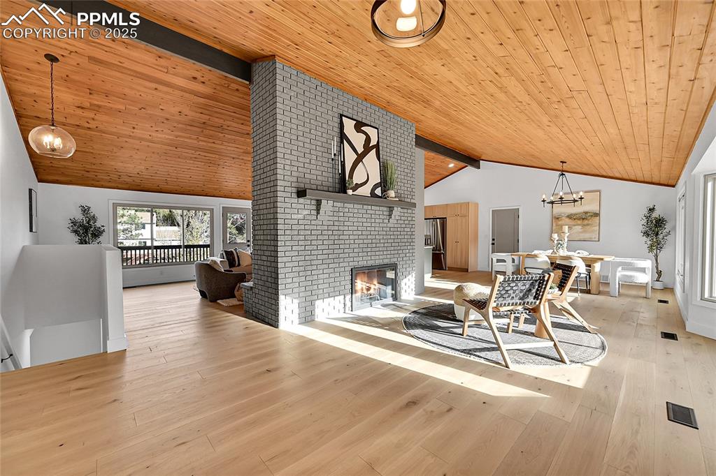 Image 3 of 40: Living area featuring a wood ceiling with exposed beams, light wood-style f
