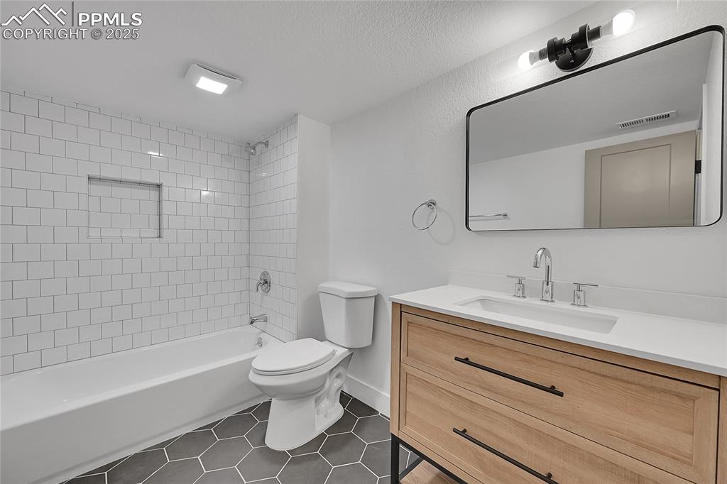 Image 35 of 40: Full bath featuring vanity, bathing tub / shower combination, and dark tile