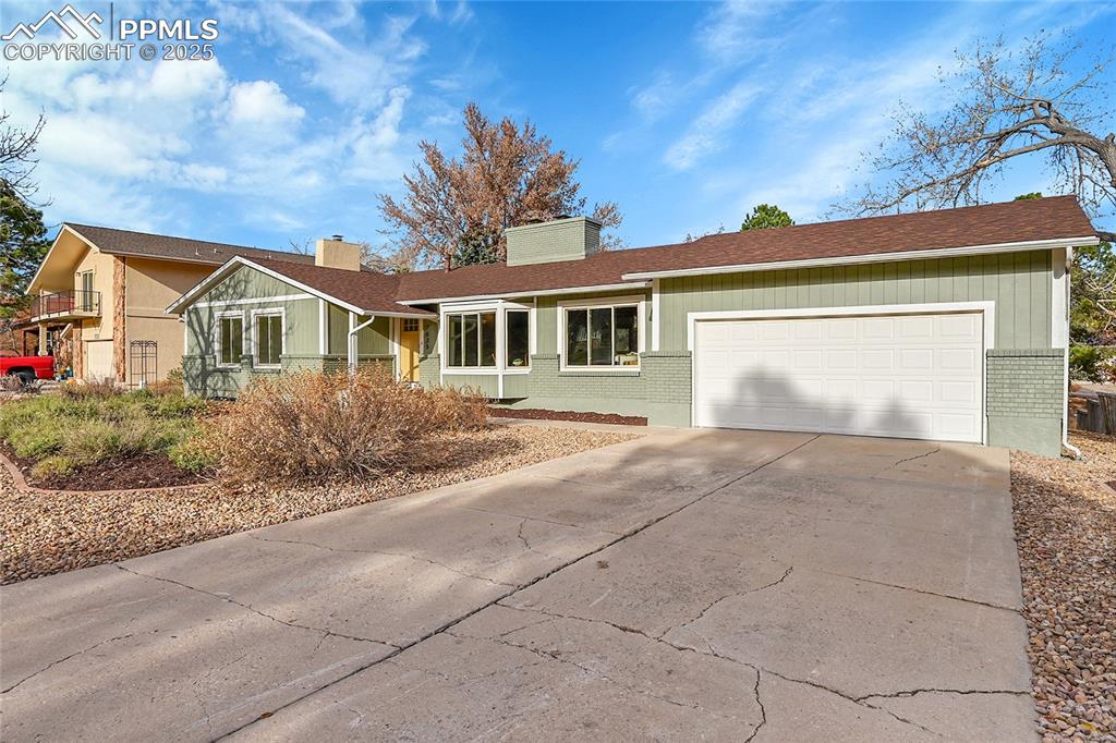 Image 5 of 40: View of front of house featuring brick siding, concrete driveway, a chimney