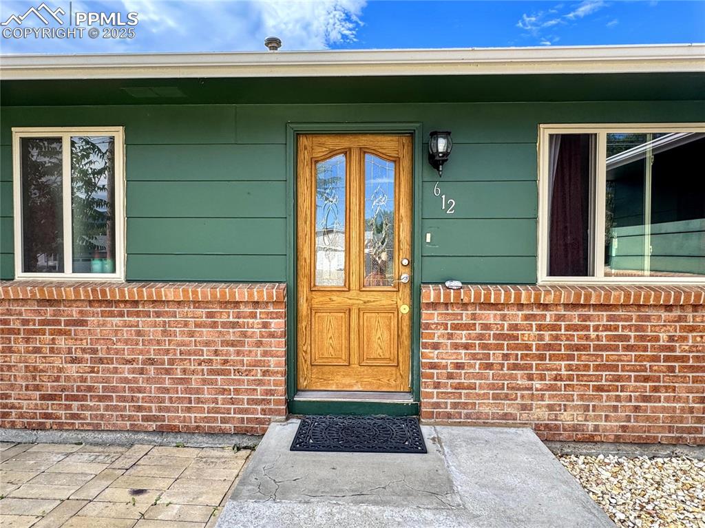 Image 3 of 8: Entrance to property featuring a porch and brick siding