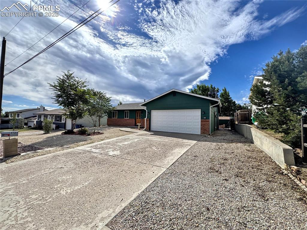 Image 4 of 8: Single story home with brick siding, concrete driveway, and an attached gar