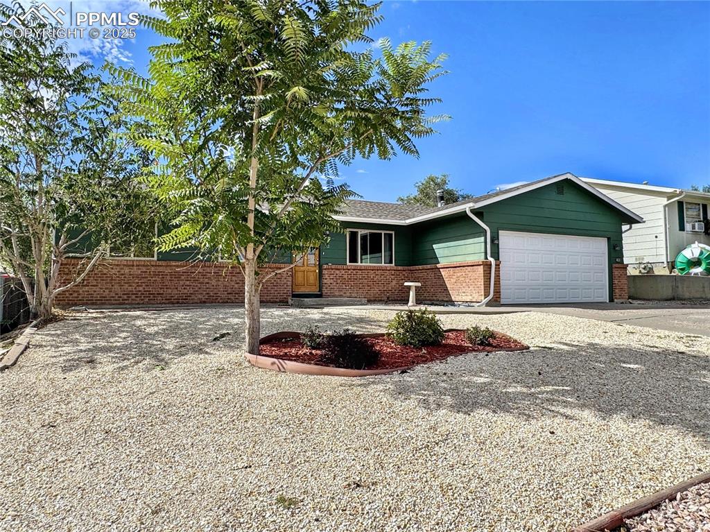 Image 5 of 8: Ranch-style home featuring brick siding, driveway, an attached garage, and 