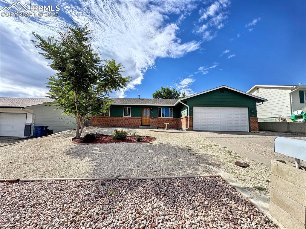 Image 8 of 8: Ranch-style house featuring brick siding, concrete driveway, and a garage