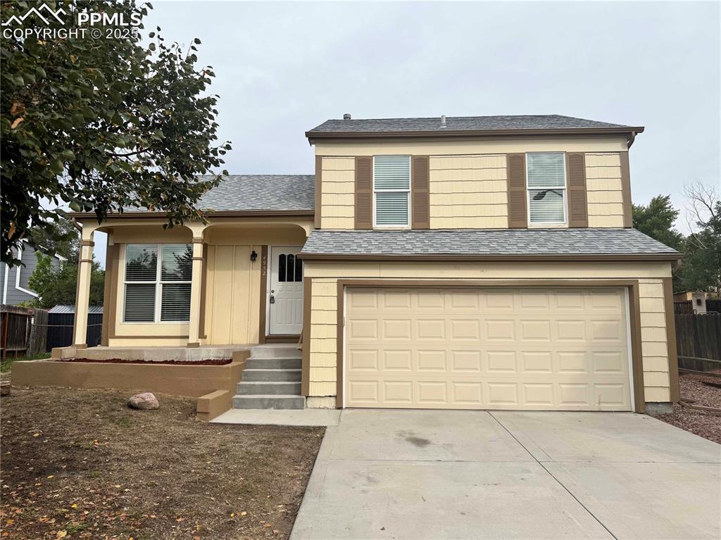 Caption: View of front facade featuring a shingled roof, driveway, and a garage