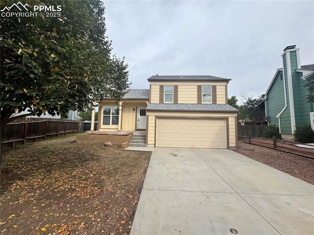 Image 2 of 24: Split level home with a garage, driveway, and a shingled roof