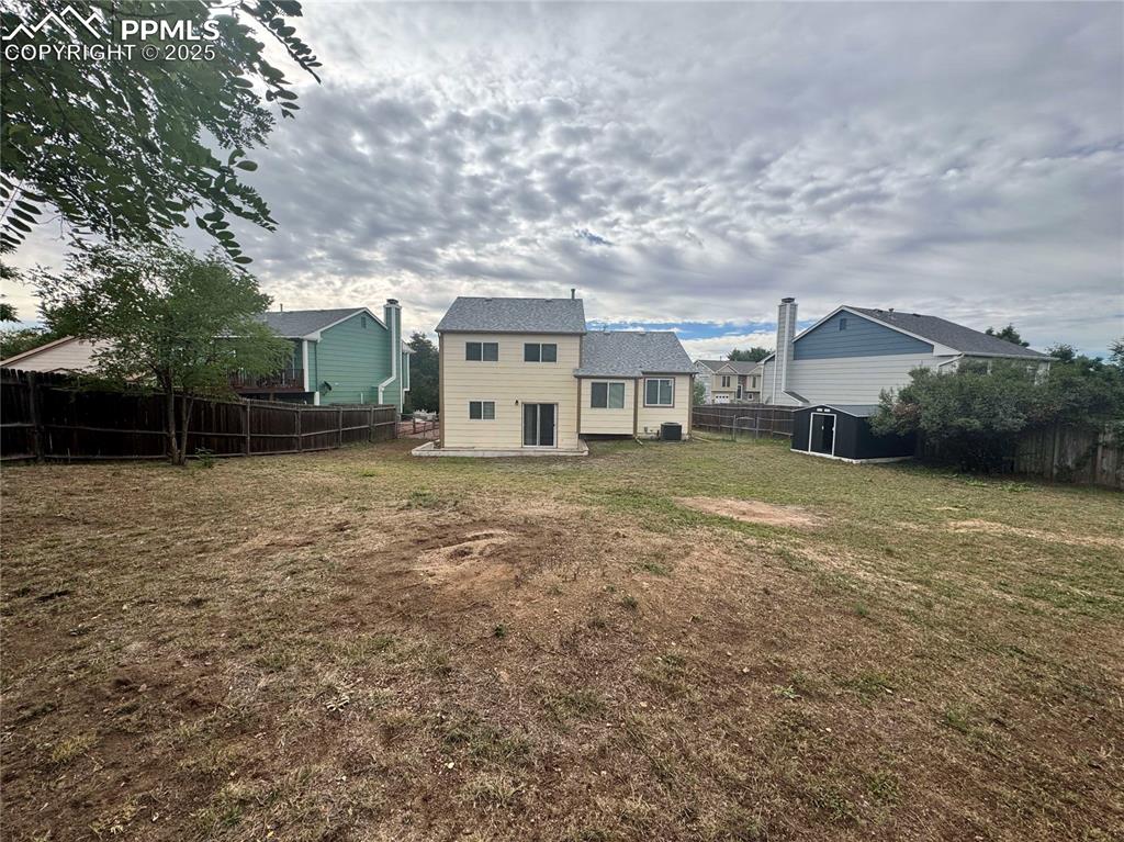 Image 5 of 24: Back of house with a fenced backyard, a patio area, and a storage shed