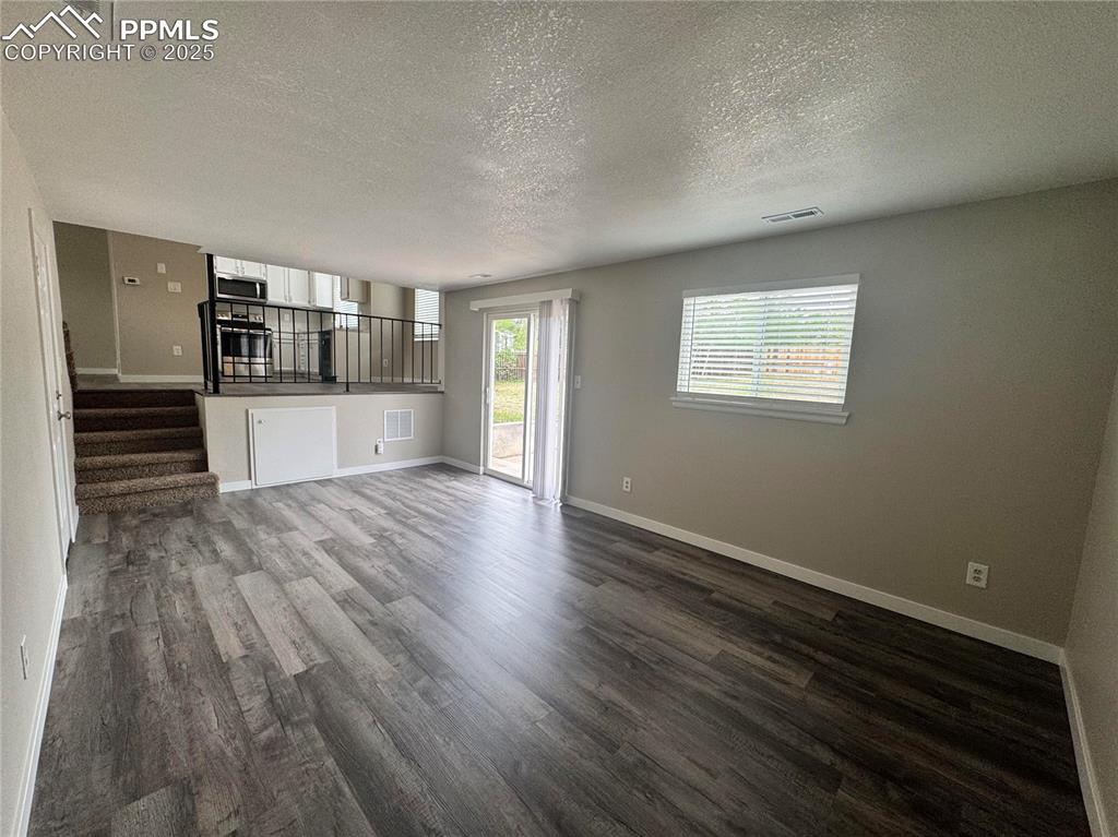 Image 7 of 24: Unfurnished living room featuring a textured ceiling, lvp flooring