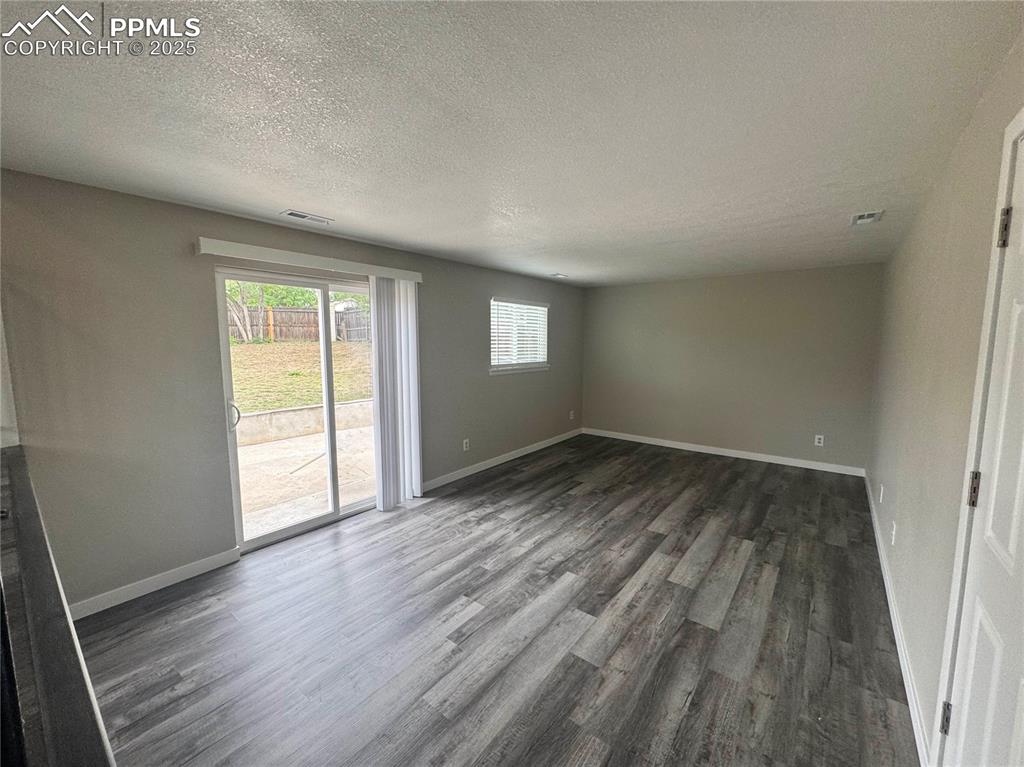 Image 8 of 24: Unfurnished living room featuring lvp flooring and a textured ceiling