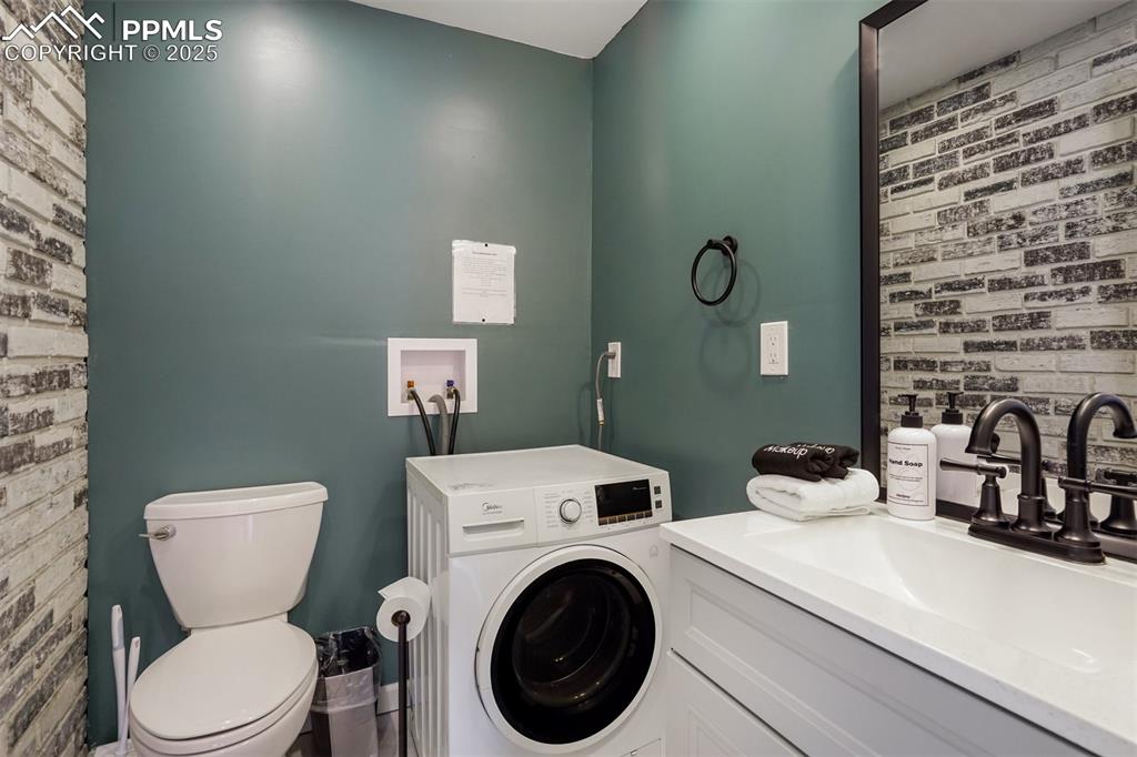 Image 11 of 31: Man level half bathroom with combo washer/dryer. 