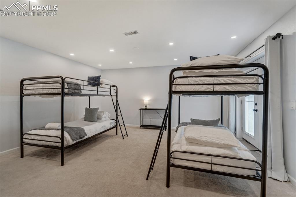 Image 21 of 31: Bedroom in the walk out basement with light colored carpet and recessed lig