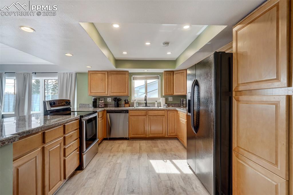 Image 6 of 31: Kitchen with a tray ceiling and recessed lights, Black and stainless steel,