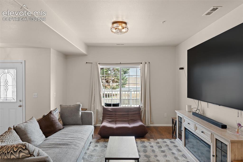 Image 10 of 32: Spacious room featuring wood-finish flooring, a decorative entryway door wi
