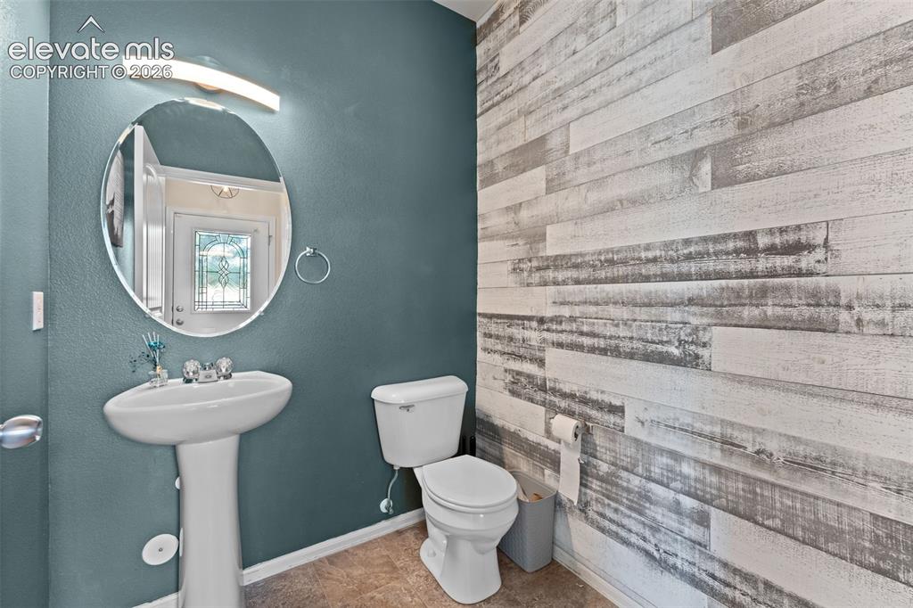 Image 15 of 32: Pedestal sink with chrome fixtures, oval wall mirror, wall-mounted light fi