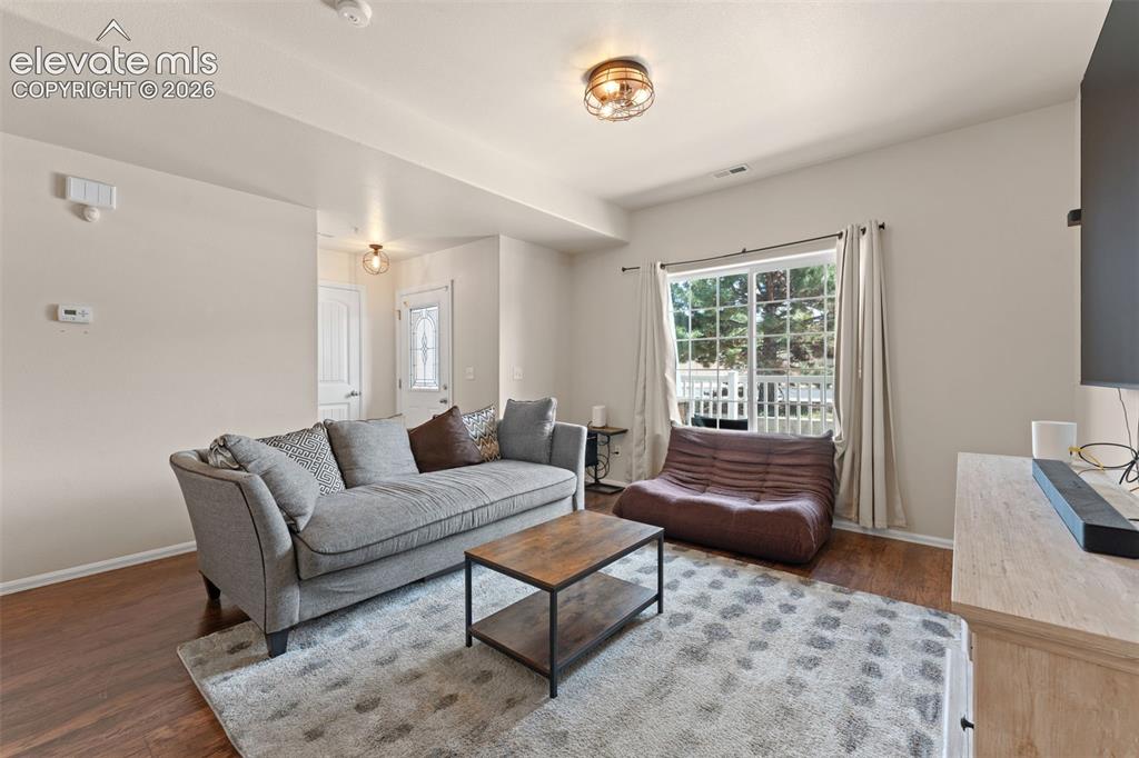 Image 2 of 32: Wood-finish flooring throughout, featuring a large window with white trim, 