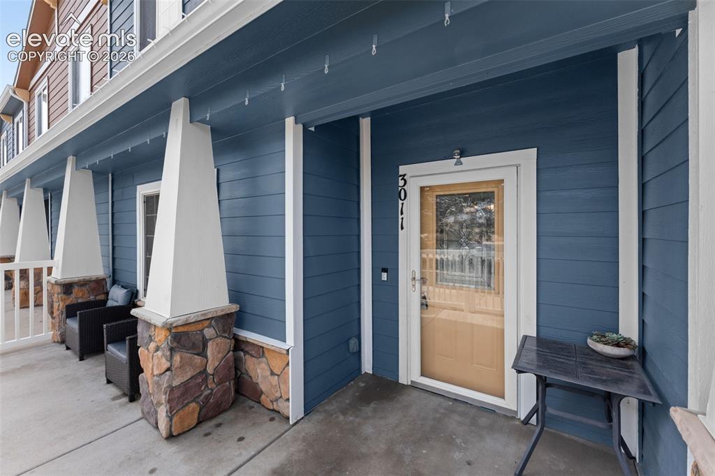 Image 6 of 32: Front entry featuring a storm door, blue siding, stone facade accents, and