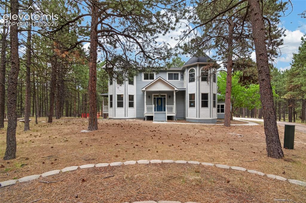 Image 3 of 46: Multi-story residence featuring a turret with arched windows, light blue si