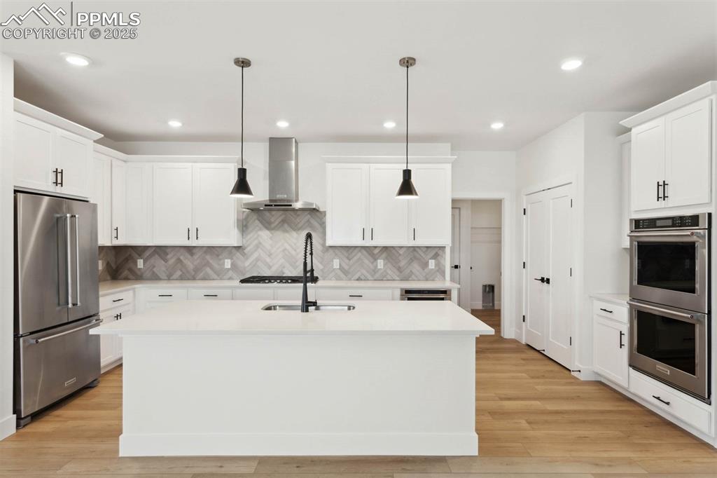 Image 2 of 15: Kitchen with light countertops, wall chimney range hood, stainless steel ap