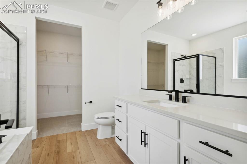 Image 6 of 15: Bathroom featuring vanity, a marble finish shower, toilet, visible vents, a