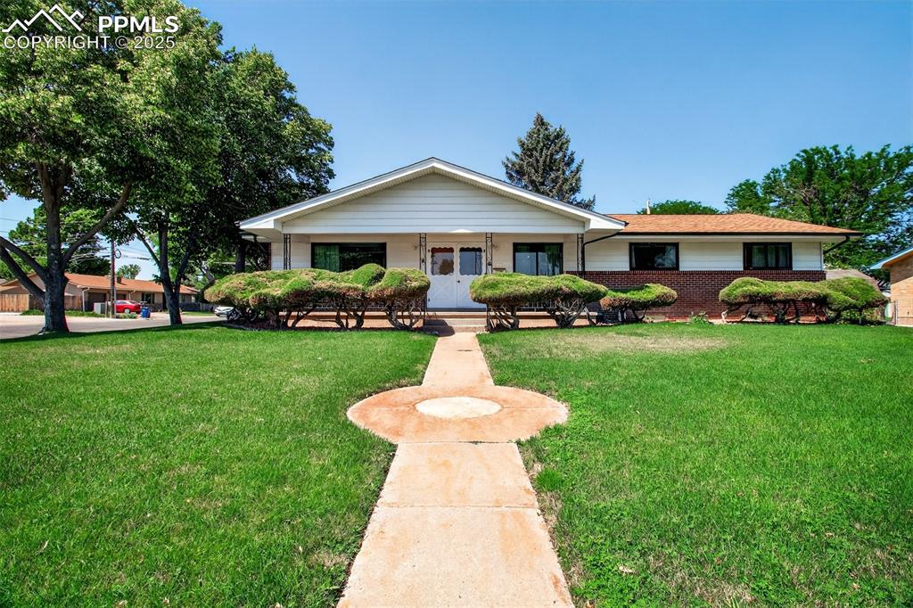 Caption: Ranch-style house featuring brick siding, a front lawn, and covered porch