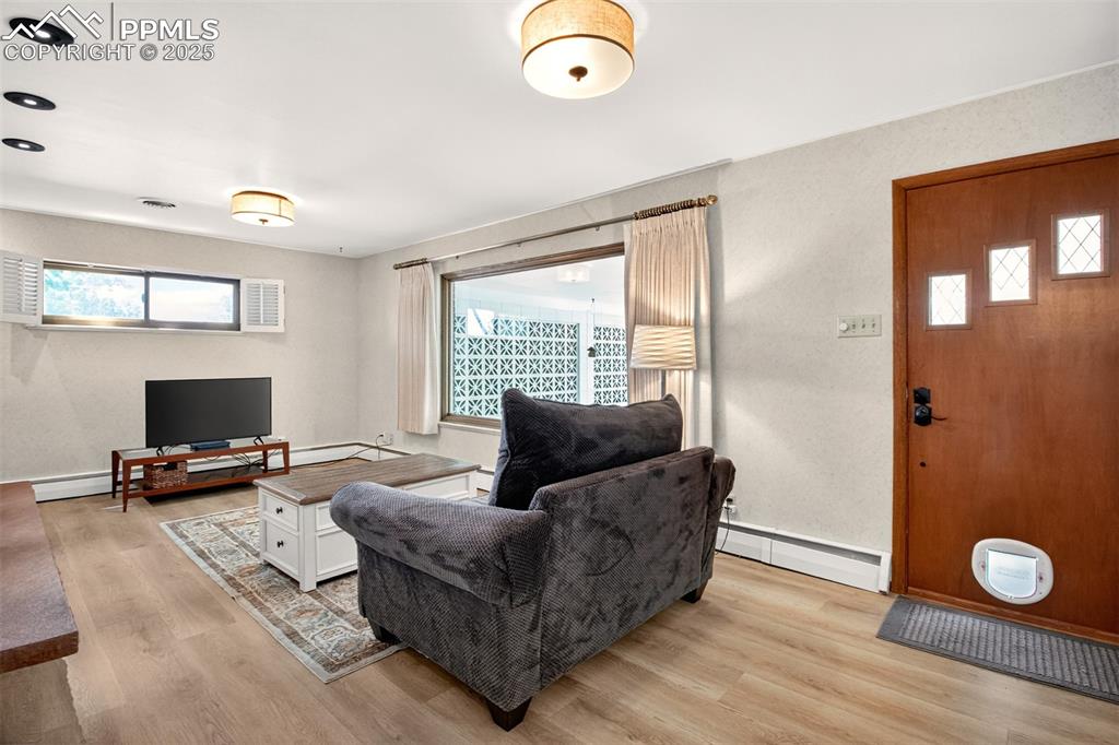 Image 11 of 43: Living area featuring a baseboard heating unit, light wood finished floors,