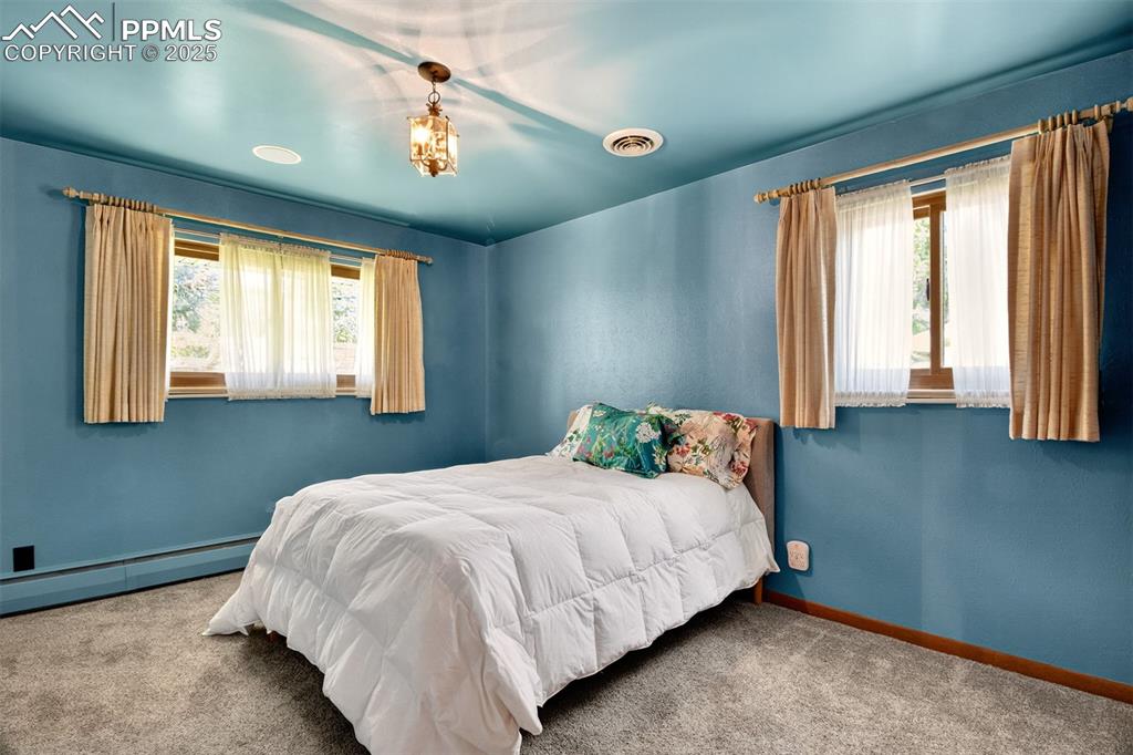 Image 14 of 43: Bedroom featuring multiple windows, carpet, and a baseboard heating unit