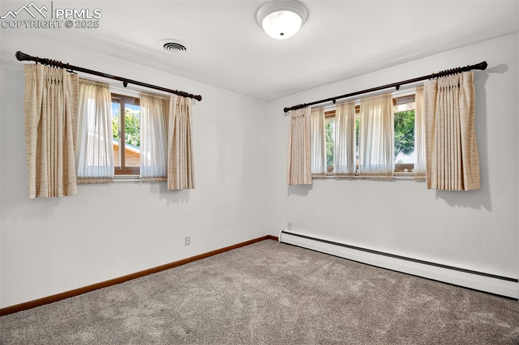 Image 17 of 43: Carpeted spare room featuring baseboard heating and healthy amount of natur