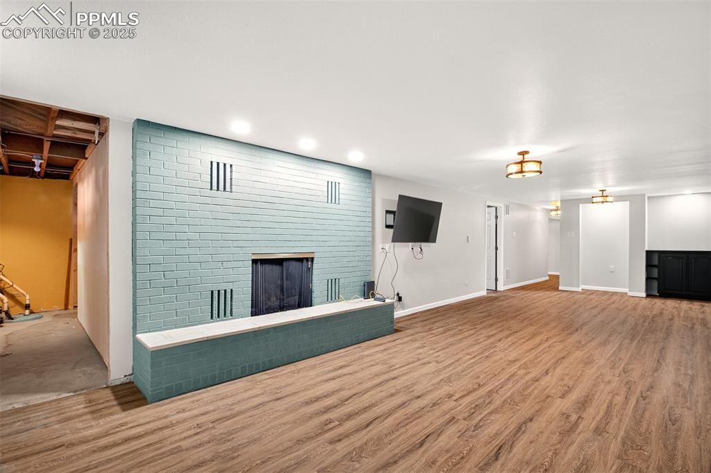 Image 20 of 43: Unfurnished living room with a fireplace, wood finished floors, and recesse