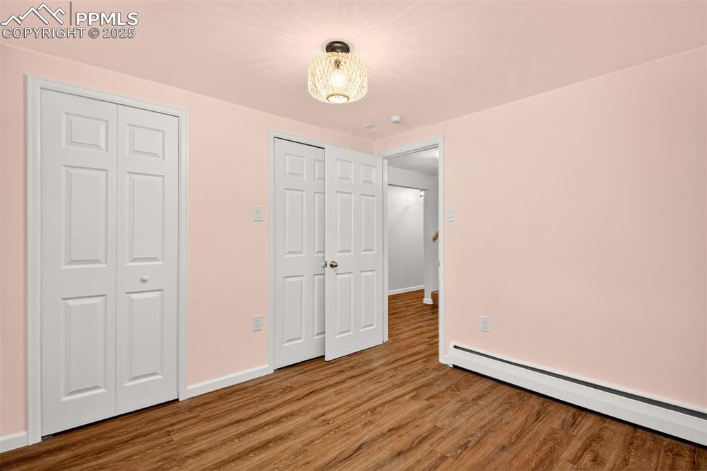 Image 22 of 43: Unfurnished bedroom featuring a baseboard radiator and wood finished floors