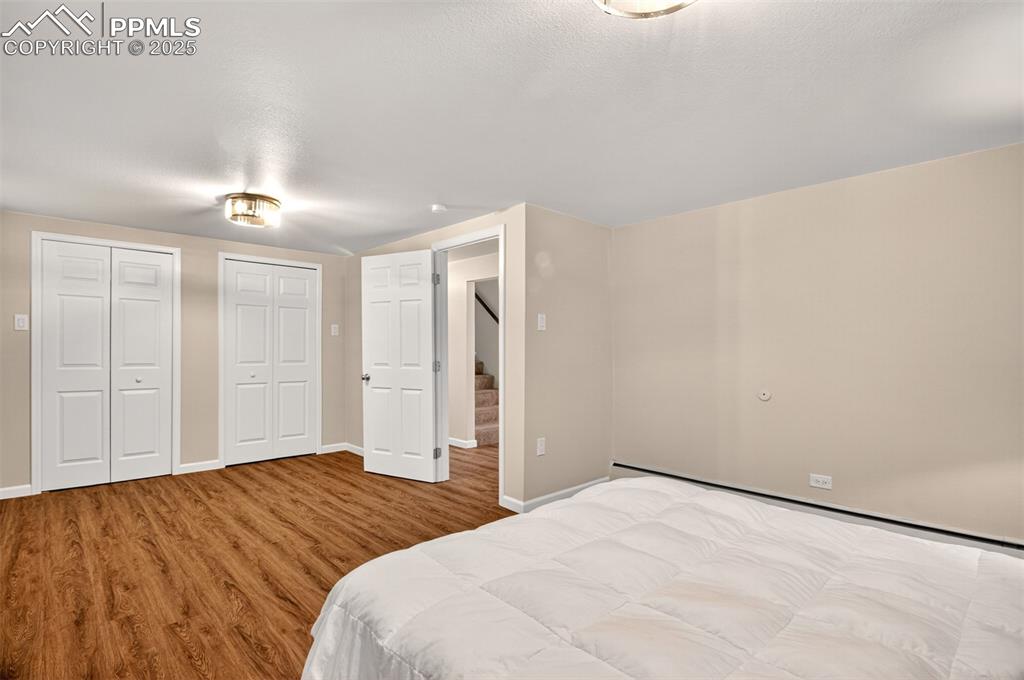 Image 24 of 43: Bedroom with two closets, wood finished floors, and baseboard heating